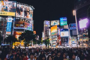 A bustling crowd at Shibuya Crossing under the bright lights of Tokyo's urban night scene.